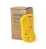 Yellow hairbrush in eco-friendly packaging with sustainability message